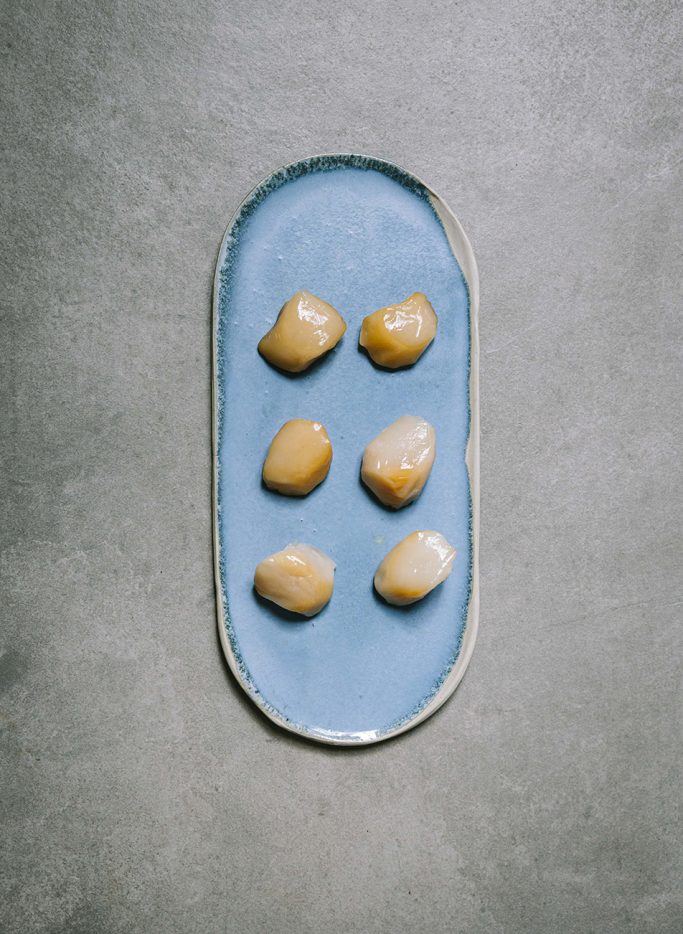 Assiette bleue avec six noix de Saint-Jacques fumées