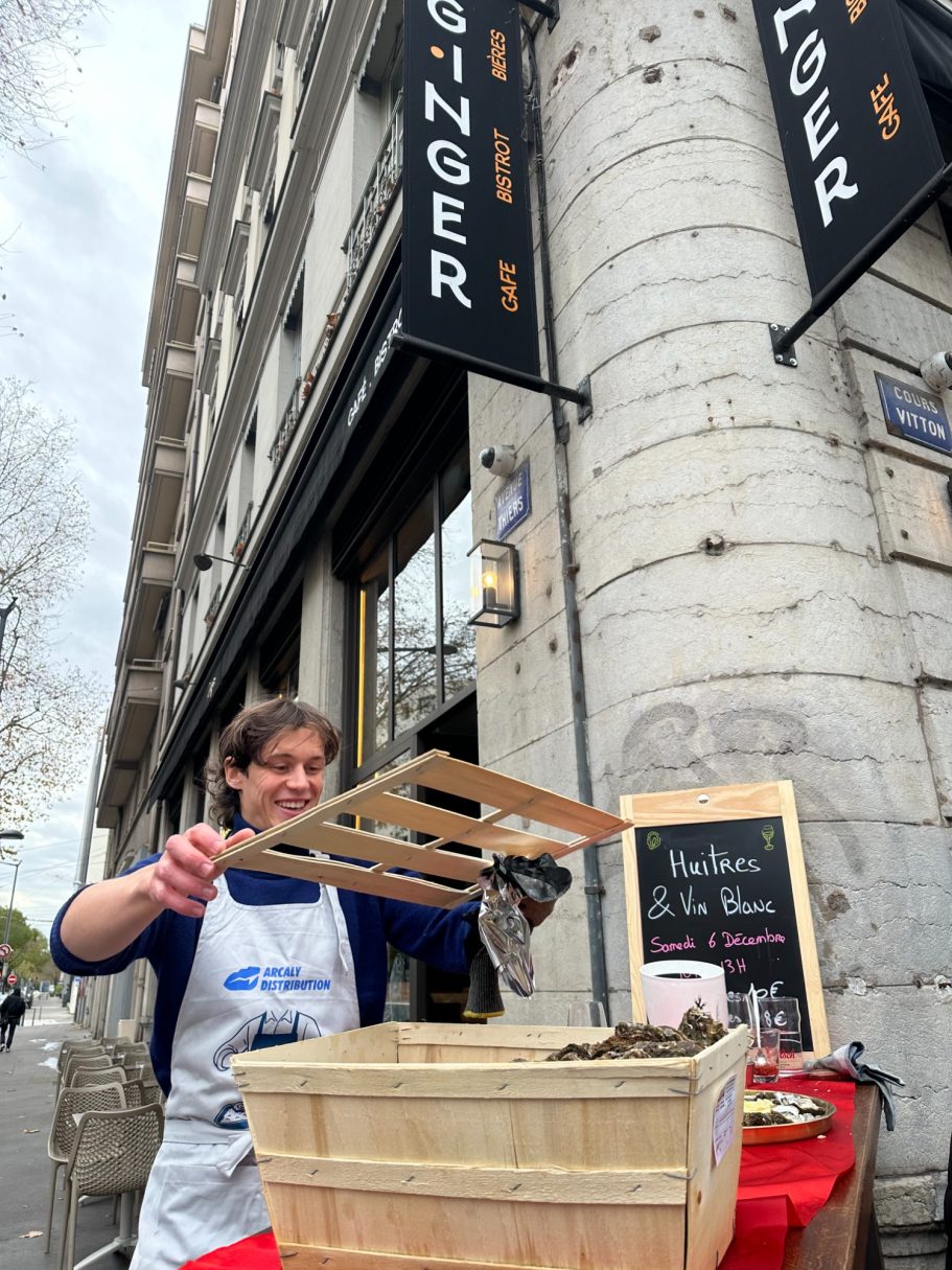 Ecailler ouvrant une bourriche d'huîtres devant un bar