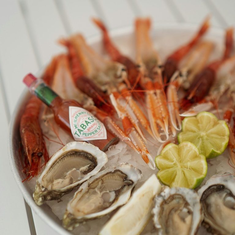 Plateau de fruits de mer avec crevettes, huîtres, quartiers de citron et sauce piquante.