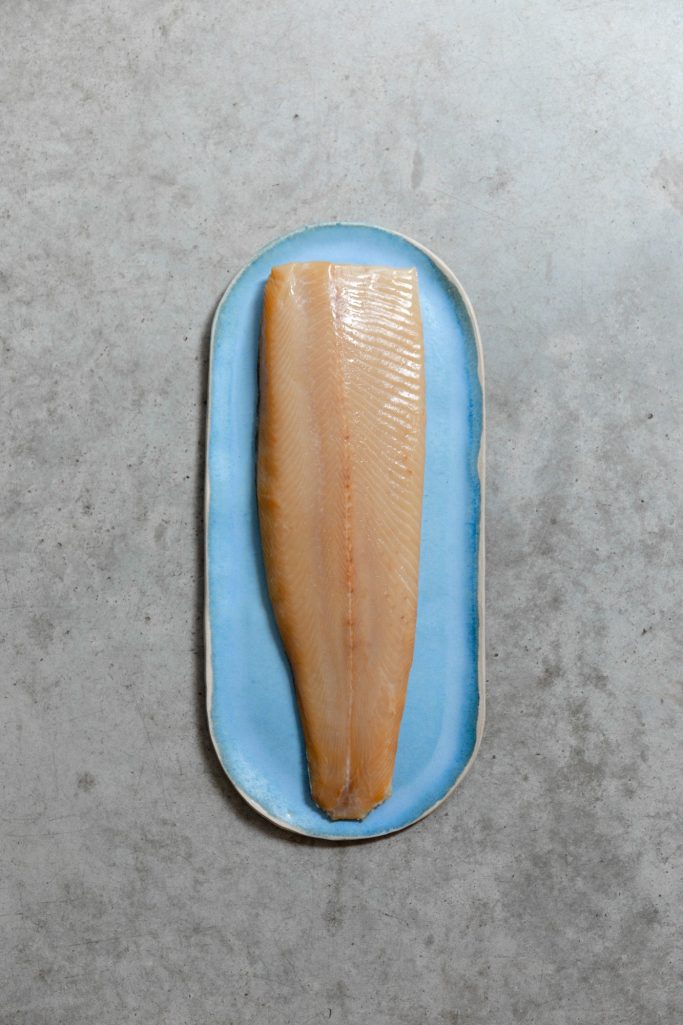 Filet de truite fumée entier dans une assiette bleue