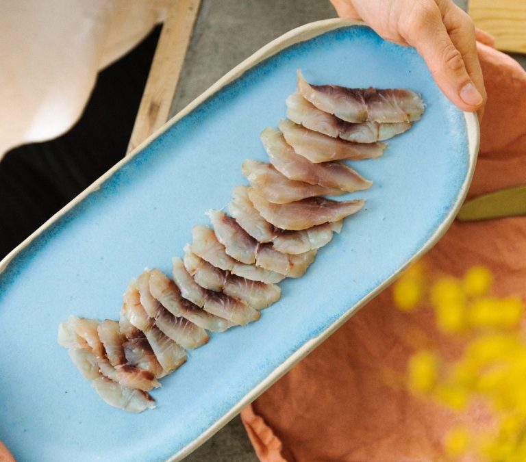 Tranche de poisson cru délicatement disposée sur une assiette bleue.