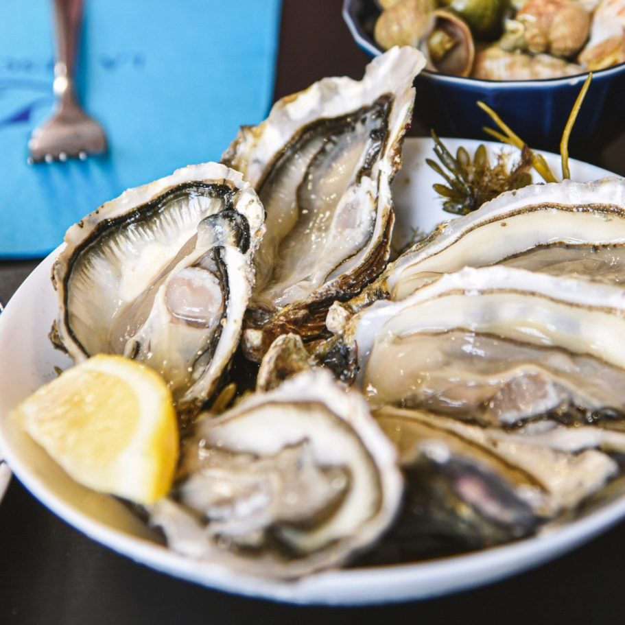 Assiette d'huîtres fraîches avec un quartier de citron.
